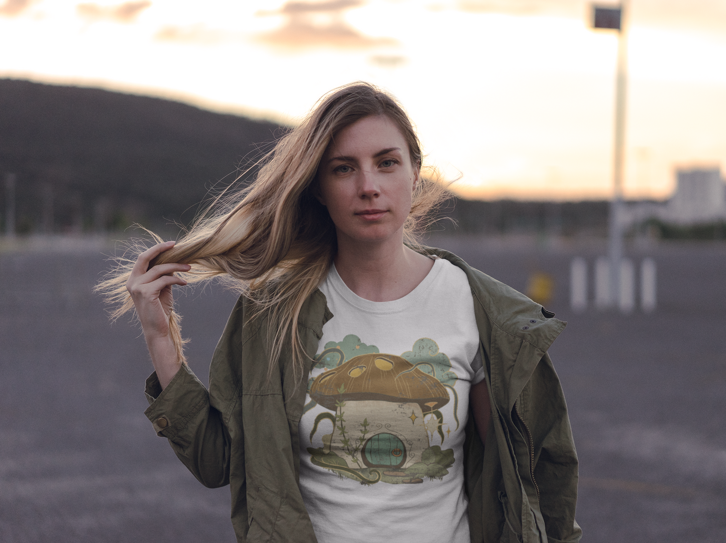 Cottagecore-inspired t-shirt featuring a cute mushroom house on the front and whimsical mushrooms on the sleeves, crafted from 100% cotton for comfort and durability